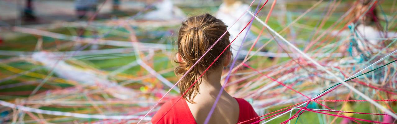 girl standing in a web of colored fiber