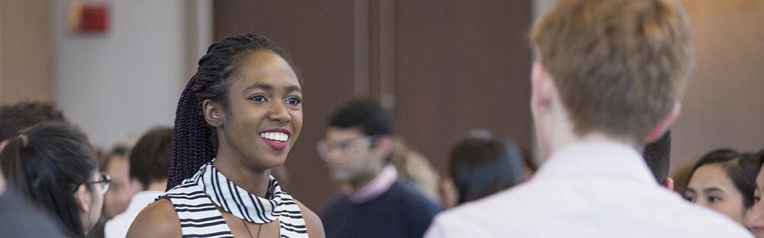 A student meets an employer at a Design Portfolio Review, Networking Reception.