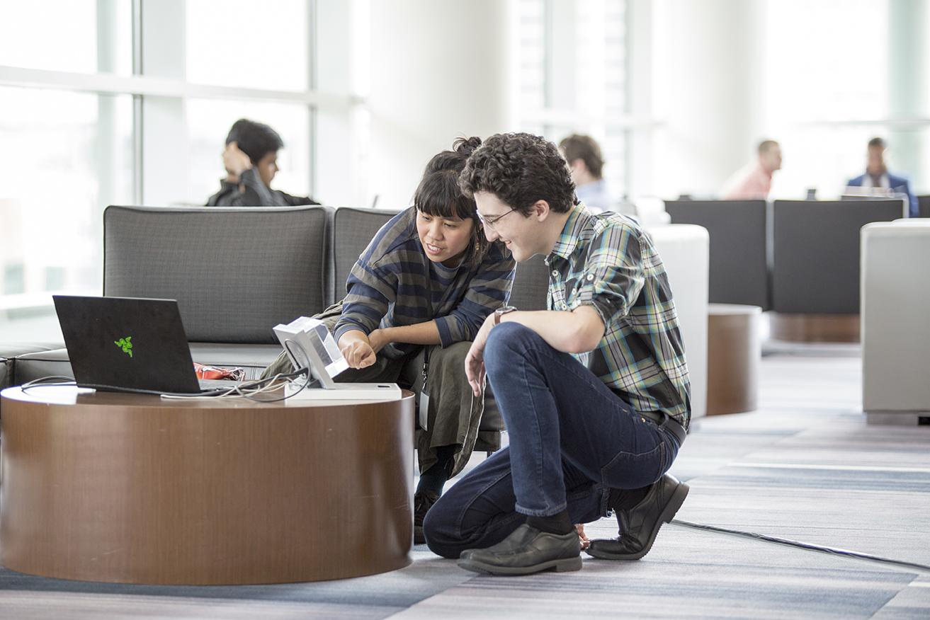A student engages with an employer in the Student Waiting Area of the Design Portfolio Review.