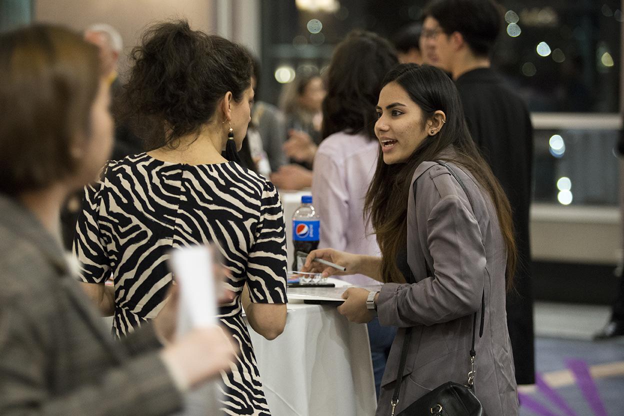 A student networks with an employer at the Design Portfolio Review, Networking Reception.